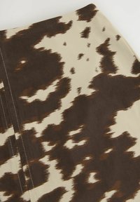 Jupe à motifs marron et crème avec une texture douce, présentant un design abstrait unique et des détails de couture visibles.