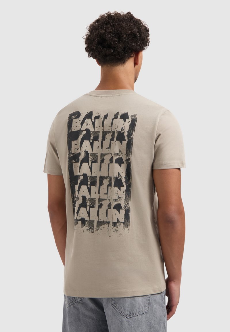 Beige katoenen t-shirt met een zwarte grafische print met de tekst "BALLIN" in herhaalde, vette letters op de achterkant. Korte mouwen, ronde hals.