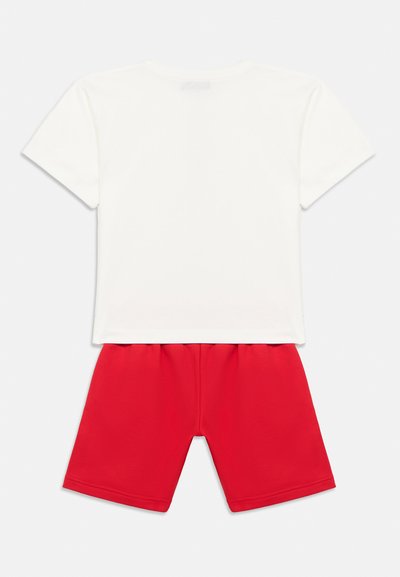 Άσπρη κοντομάνικη μπλούζα σετ με κόκκινα σορτς με ελαστική μέση, απλωμένα σε λευκό φόντο.