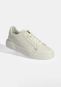 White leather sneakers with textured finish, round toe, and flat rubber sole. Features lace-up front and contrasting stitching detail.