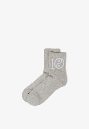 Hellgraue, gerippte Crew-Socken mit weißer "10" und Yin-Yang-Symbol an der Seite, flach auf einem weißen Hintergrund liegend.