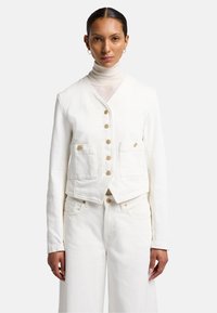 Witte denim jack met een cropped ontwerp, voorzien van knopen, twee voorzakken en een gestructureerde kraag. Draagt over een lichte coltrui.