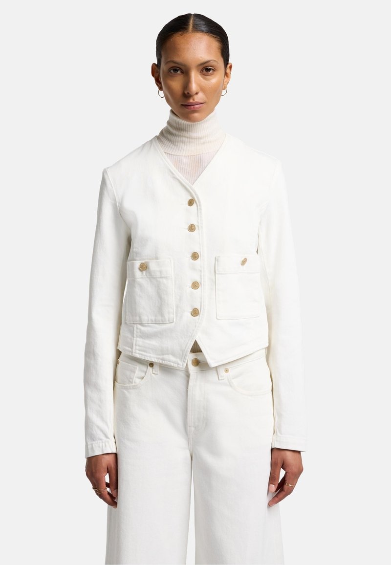 Witte denim jack met een cropped ontwerp, voorzien van knopen, twee voorzakken en een gestructureerde kraag. Draagt over een lichte coltrui.