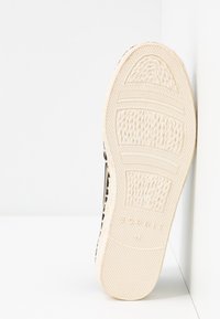 Semelle d'une chaussure beige clair avec une adhérence texturée et à motifs, et le nom de la marque "Esprit" embossé près du talon.