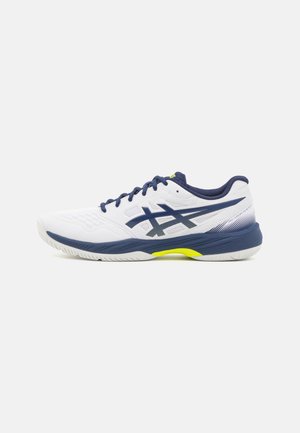Zapatilla deportiva blanca con acentos en azul marino, parte superior texturizada, logotipo gris contrastante y detalle amarillo brillante en la suela. Diseño de perfil bajo.