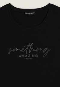 Camiseta de algodón negra con cuello redondo, que presenta un gráfico plateado brillante que dice "algo ASOMBROSO" en lettering cursivo y en bloque.