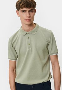 Kortærmet polo t-shirt i lysegrøn, med et tekstureret mønster, tre-knaps placket og hvide accenter på ærmerne.