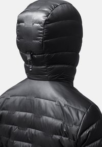 Zwarte gewatteerde jas met een gestructureerd oppervlak en een slimfit capuchon. Kenmerken zijn horizontale stiksels en een aansnoermechanisme bij de hals.