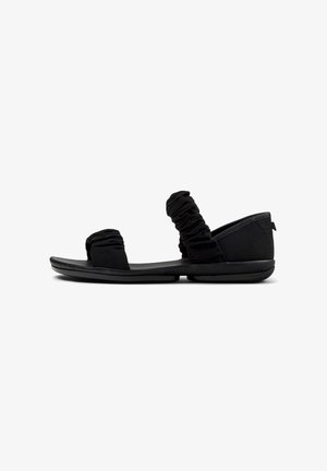 Zwarte sandalen met geraffineerde stoffen banden, platte zool, zachte textuur en afgerond ontwerp, met minimalistische accenten en geen hardware.