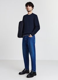 Marineblaues Langarm-Sweatshirt, blaue Denim-Jeans, schwarze Lederschuhe. Einfaches Design mit lässiger Passform und subtilen Texturen.