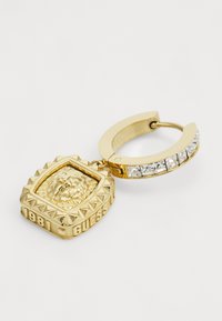 Gold hoop earring with a textured lion medallion, spiked border, and "1981 GUESS" engraving. The hoop features clear rhinestone accents.