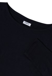 Mörkblå, kortärmad t-shirt i mjukt tyg med rund halsringning och en etikett som säger "CECI." Enkel, slät struktur.