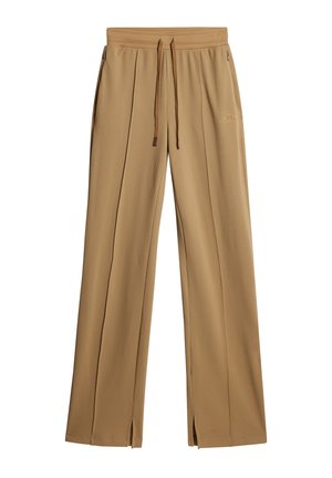 Pantalons larges en beige clair, texturés, avec une taille à cordon et des fentes sur les côtés. Présente un logo discret.
