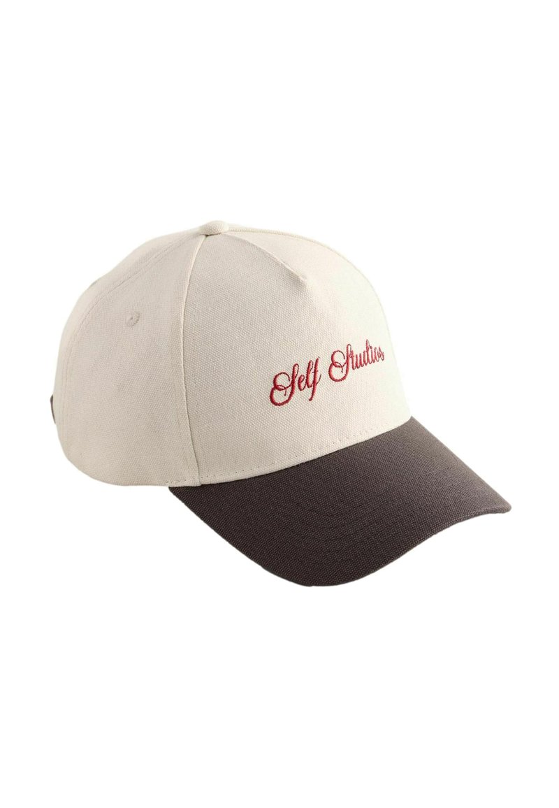 Gorra de béisbol con corona de color beige claro, visera marrón oscuro y texto bordado en rojo "Self Studios" en el frente. Material de algodón, diseño estructurado.