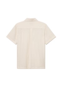 Chemise à manches courtes en tissu texturé beige clair, avec un col pointu et des détails de plis au dos, coupe droite et sans quincaillerie visible.