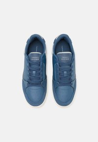 Siniset nahkakengät, joissa on yleiset rei'itykset, harmaat yksityiskohdat ja nauhakiinnitys. Sisältää 'TOMMY HILFIGER' -logon kielekkeessä. Kumipohja.