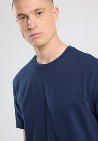 Navy blue puuvillane T-särk ümarate kaelustega ja lühikeste varrukatega, millel on sile tekstuur ja lihtne disain ilma mustrite ja aktsentideta.