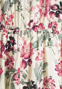 Tissu floral présentant des fleurs roses, rouges et noires sur un fond écru, avec une taille froncée et une finition douce et texturée.