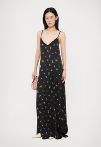 Schwarzes Maxikleid mit dünnen Trägern, das ein lebhaftes Blumen- und Objektmuster zeigt. Glatte Stoffqualität, tiefer V-Ausschnitt und fließende Silhouette.