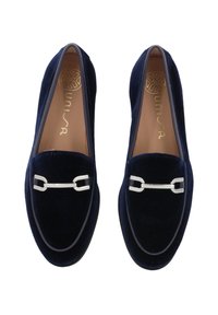 Mocassini in velluto blu navy con una texture liscia. Presentano dettagli in metallo argento e punta arrotondata. Fodera interna in pelle e suola con un leggero contrasto.