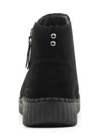 Stivale alla caviglia in suede nero con punta arrotondata, suola in gomma testurizzata e due dettagli in argento sul retro vicino a una cerniera.