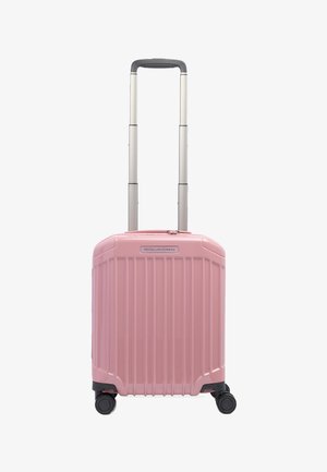 Maleta rígida compacta de color rosa con estrías verticales, mango telescópico plateado extendido, cuatro ruedas giratorias negras y logotipo de la marca en el frente.