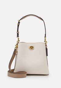 Valkoinen nahkalaukku, jossa on muotoiltu rakenne, ruskeat yksityiskohdat, kultaiset metalliosat ja irrotettava hihna. Edessä on logoyksityiskohta.