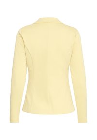 Blazer jaune pâle sur mesure avec manches longues, coutures structurées et col à encoches, présenté de dos sur fond blanc.