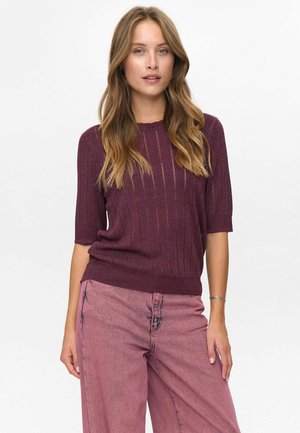 Burgundy knitted top with short sleeves and vertical stripes, paired with light pink loose-fitting pants, featuring a textured fabric.