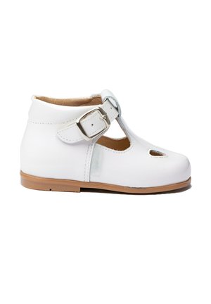 Zapato infantil de cuero blanco con hebilla de correa en T y dos pequeños orificios de ventilación en la puntera, suela color marrón claro y forro interior suave.