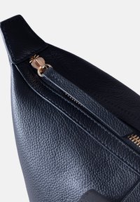 Black leather pouch with a textured surface, featuring a gold zipper and pull tab, angled view showcasing stitching and design details.