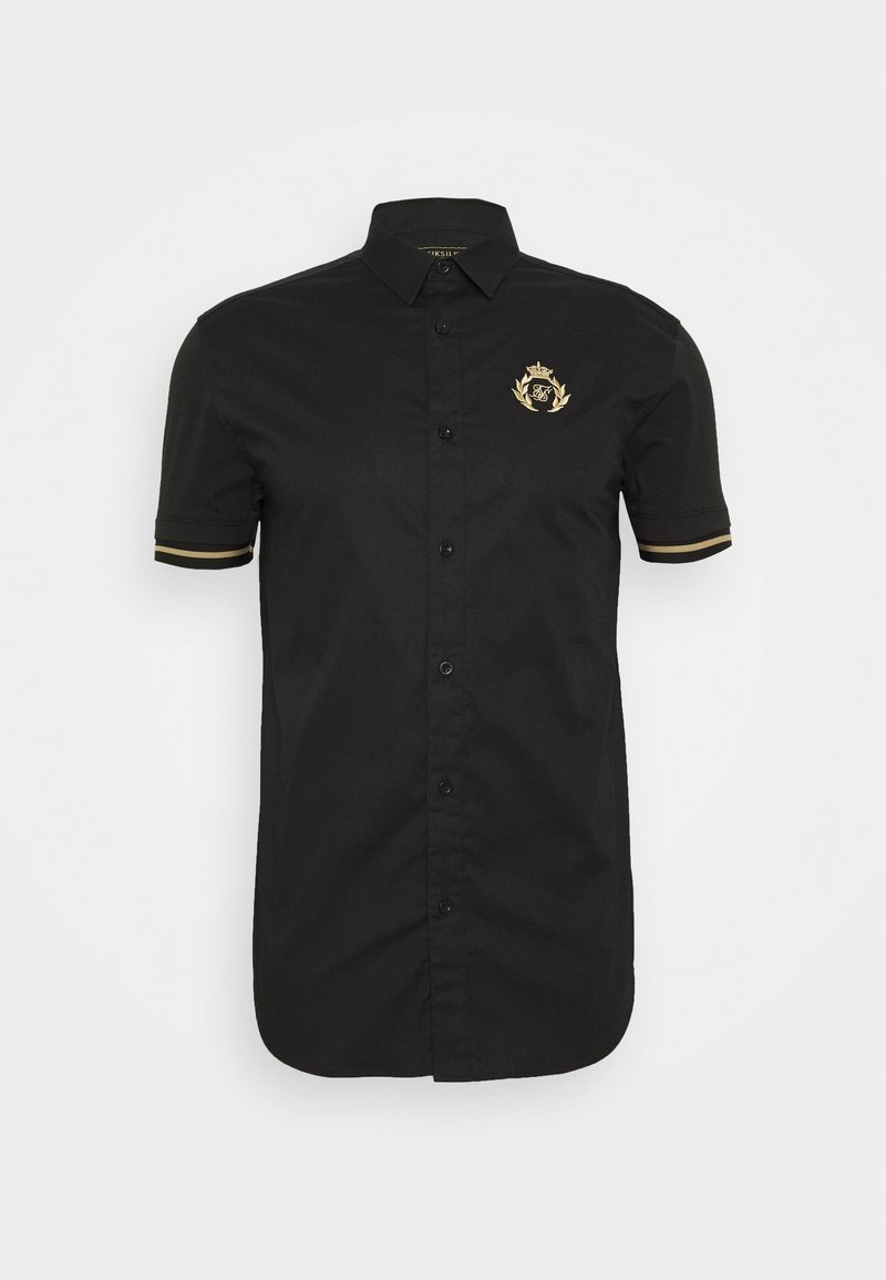 Musta lyhythihainen paita, joka on valmistettu sileästä kankaasta, ja jossa on kultainen symboli vasemmassa rinnassa sekä erottuvat kultaiset raidat hihoissa.