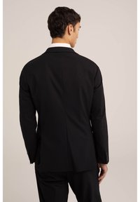 Veste de costume noire au design classique, avec un revers cranté, une texture lisse et des poignets boutonnés. La vue arrière révèle une coupe structurée.