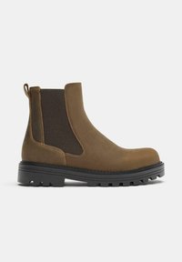 Hnedé členkové topánky z semišu s elastickými bočnými panelmi, zaoblenou špičkou a pevnou čiernou gumovou podrážkou s obrusovým vzorom. Na päte je pútko na ťahanie.