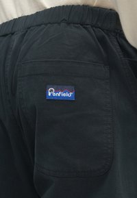 Μαύρο παντελόνι από μαλακό υλικό με ελαστική μέση, με μια πίσω τσέπη και ένα πατς λογότυπου Penfield σε μπλε και κόκκινο χρώμα.