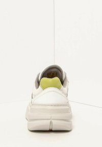 White sneaker with a textured mesh body, gray accents, and a green heel tab. Thick white sole with raised sections at the back.