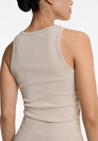 Beige geripptes Tanktop mit Rundhalsausschnitt, das eine figurbetonte Passform und breite Träger hat. Glatte Textur mit subtilen Nähten.