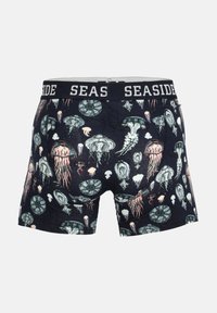 Boxer da uomo con uno sfondo scuro e un motivo di varie illustrazioni di meduse in tonalità di blu, rosa e bianco. Elastico nero con la scritta "SEASIDE".