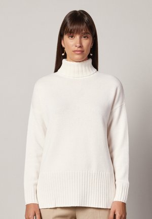 Hvid turtle neck sweater med ribbet kant og ærmekanter, lavet af blødt materiale, med en afslappet pasform og lange ærmer.