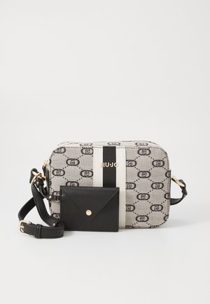 Borsa a mano rettangolare con tessuto beige a motivo e dettagli in pelle nera, caratterizzata da un logo dorato, una tasca frontale e una tracolla regolabile.