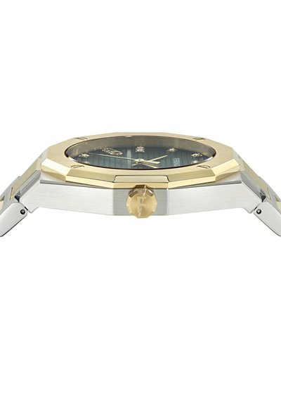 Karcsú, két tónusú karóra arany nyolcszögletű lünettával, ezüst tok, fekete számlap arany mutatókkal, és egy "F" betűvel gravírozott arany korona.