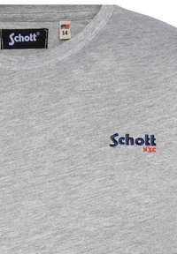 Camiseta de algodón gris con cuello redondo y logo bordado "Schott NYC" en azul marino y rojo en el lado izquierdo del pecho. Etiqueta de tamaño visible.