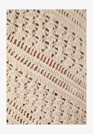 Textil tejido que presenta un color crema con intrincados patrones calados, texturizado y en capas con un fino fondo marrón.