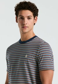 Gestreepte T-shirt met korte mouwen in blauw, rood en wit. Heeft een marineblauwe geribbelde kraag en een klein logo op de borst. Zacht textielmateriaal.