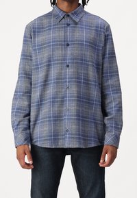 Camicia a button-up in plaid blu, con colletto, maniche lunghe e vestibilità rilassata. Realizzata in tessuto testurizzato con una leggera lucentezza.