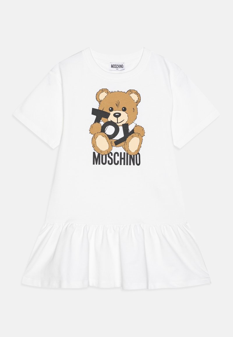 Robe blanche à manches courtes avec ourlet volanté, présentant un ours en peluche tenant des lettres formant "TOY" et le nom de la marque "Moschino" en dessous.