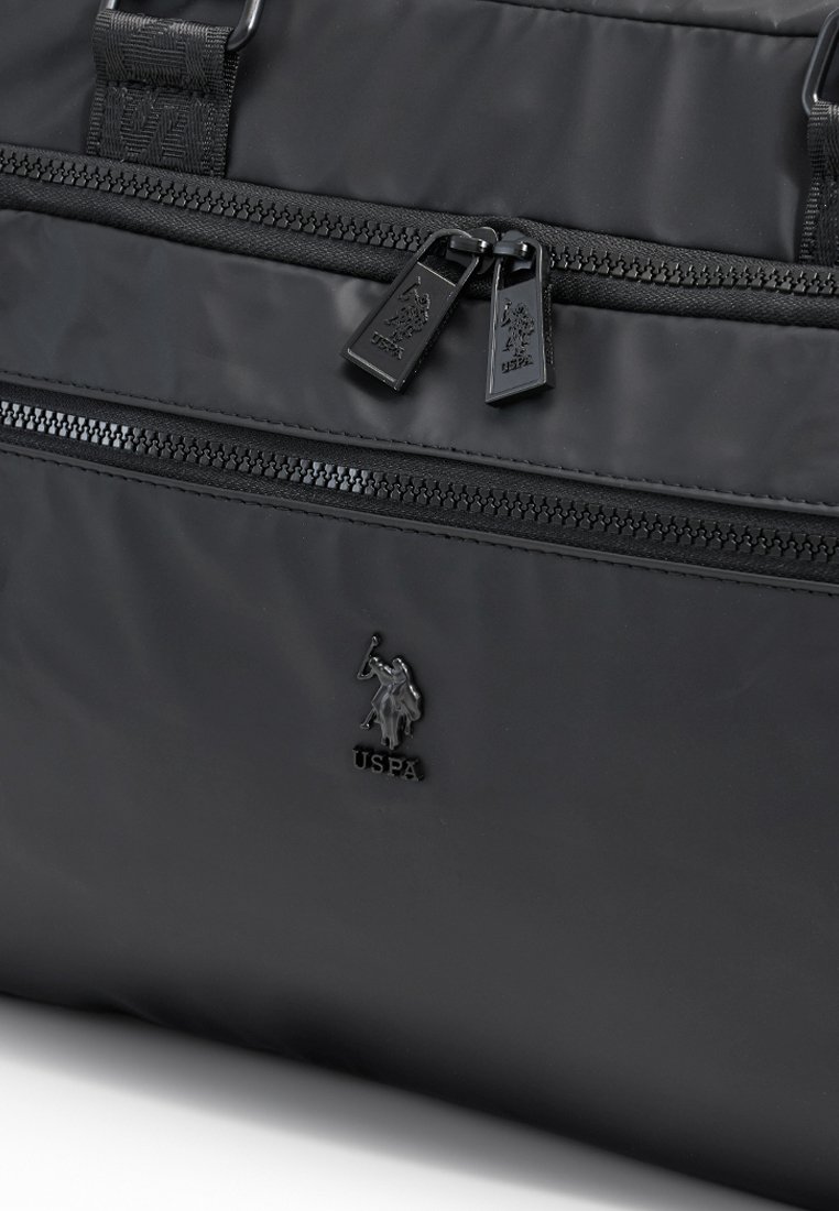 Černá nylonová sportovní taška s dvojitými kapsami na zip, tkaným popruhem a lesklým logem. Hladká textura s pevnými kovovými detaily.