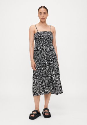 Rochie midi negre cu imprimeu floral, cu bretele ajustabile și un decolteu elastic. Asortată cu sandale negre cu platformă groasă și ținte.