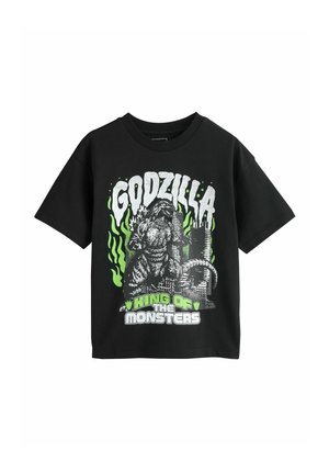 Black T-shirt with Godzilla graphic, green flames, city ruins, and text "KING OF THE MONSTERS" in white and green letters.