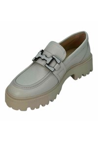 Mocassino in pelle beige chiaro con punta arrotondata, accentato da hardware nero, e una suola in gomma beige spessa con un motivo testurizzato.